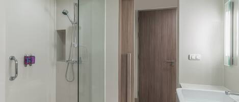 A modern bathroom with a glass-enclosed shower, a wooden door, and a white sink.