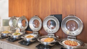 A buffet line with various food items in stainless steel bowls, set against a wooden wall. - Travelodge Pattaya (Pattaya)