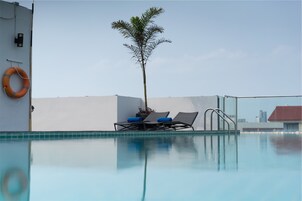 Una piscina al aire libre, sillones reclinables de piscina