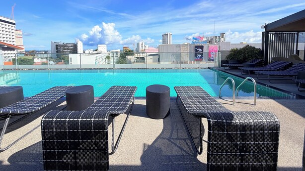 A rooftop pool with lounge chairs and a city view. - Travelodge Pattaya (Pattaya)
