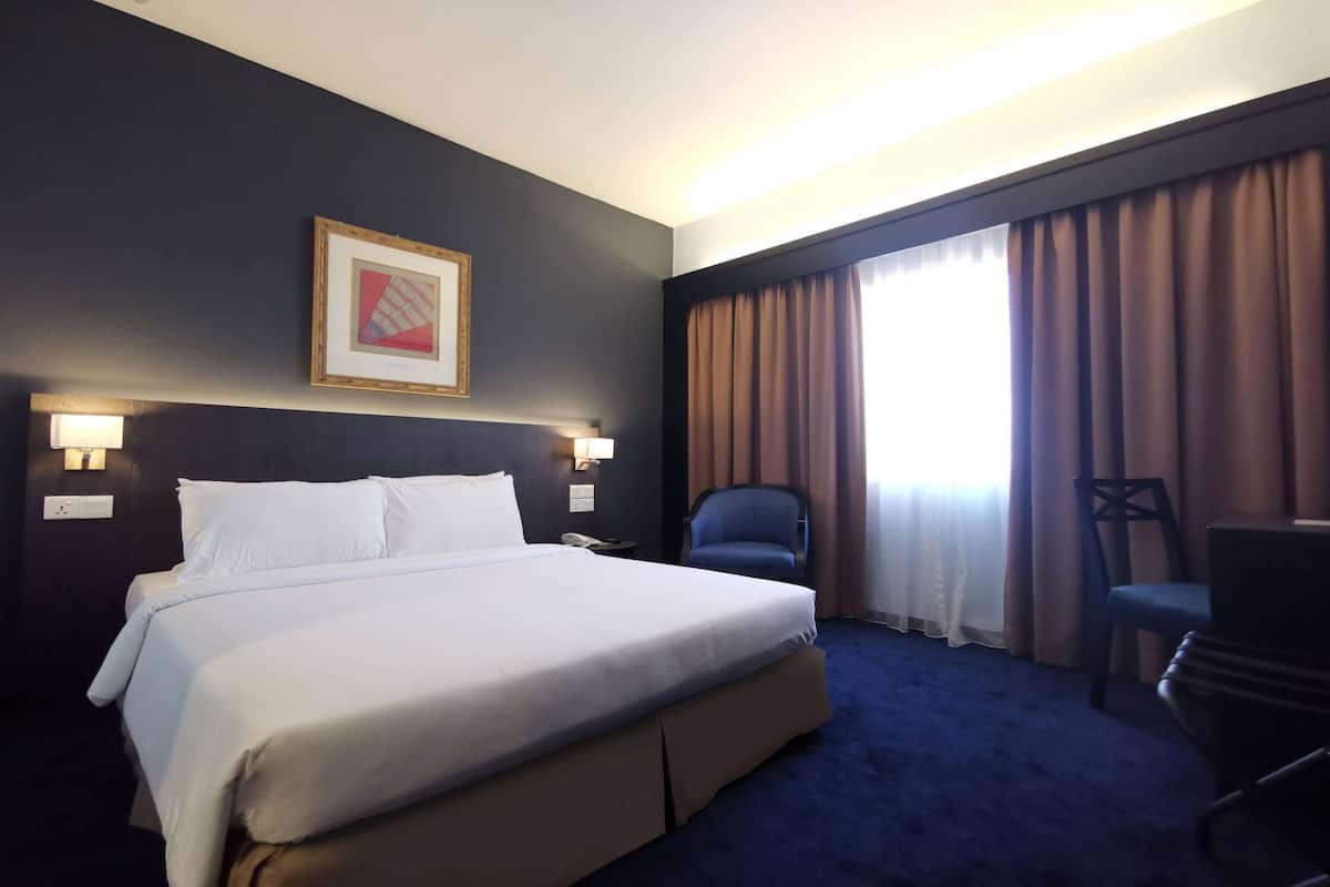 Ein Hotelzimmer mit einem großen Bett, einem Schreibtisch, einem Stuhl und einem gerahmten Bild an der Wand.