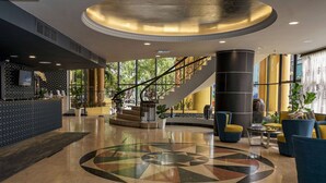 A spacious lobby with a central staircase, a reception desk, and seating areas. - Shahzan Hotel Kuantan, Trademark Collection by Wyndham (Kuantan)
