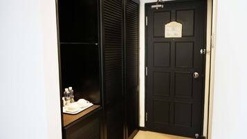 Habitación de hotel con una puerta negra, una mesita con artículos de aseo y un armario oscuro.