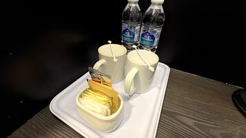 Una bandeja con dos tazas blancas, una taza de café blanca y dos botellas de agua.