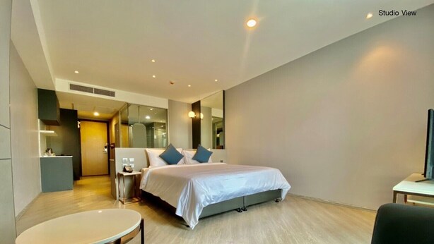Quarto de hotel moderno com uma cama grande, uma escrivaninha e uma área de estar.