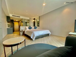 Una habitación de hotel moderna con una cama grande, un escritorio y una zona de estar.
