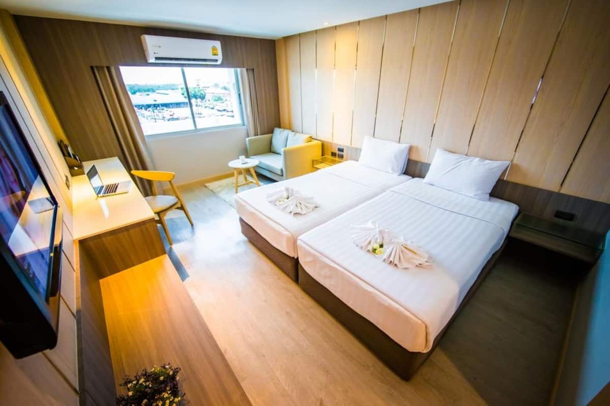 A hotel room with a bed, a desk, a chair, a small table, and a window.