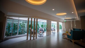 Um saguão de hotel moderno com divisória de vidro, área de estar e luminárias circulares e originais.