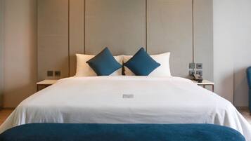 A hotel room with a large bed, two pillows, a bedside table with a lamp, and a nightstand.