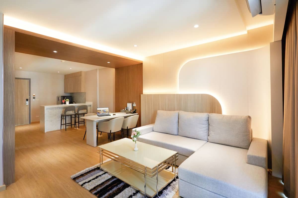 A modern living room with a sofa, a coffee table, and a dining area with chairs and a table.