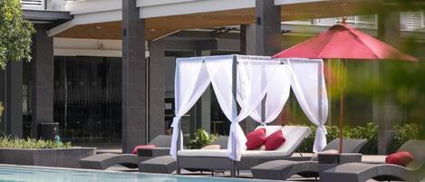 Una piscina al aire libre, sillones reclinables de piscina