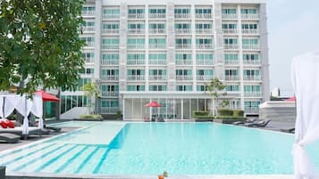 Un hotel con una piscina grande, varios balcones y zonas de estar al aire libre.