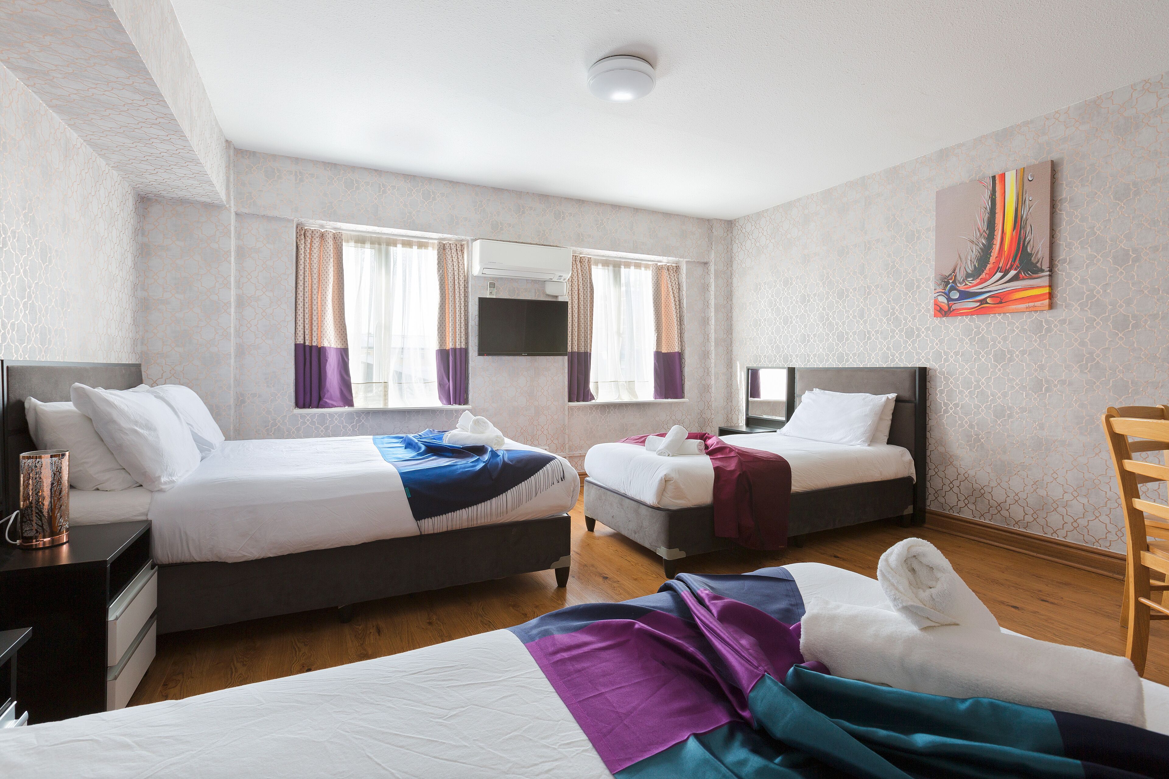 Quarto de hotel com duas camas, uma televisão e um quadro na parede.