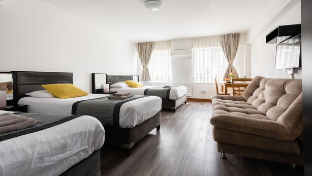 A hotel room with two beds, a sofa, a TV, and a dining area with a table and chairs. - Central Hoxton Shoreditch (London)