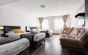 A hotel room with two beds, a sofa, a TV, and a dining area with a table and chairs. - Central Hoxton Shoreditch (London)