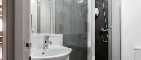 Een badkamer met een witte wastafel, een spiegel en een douchecabine.