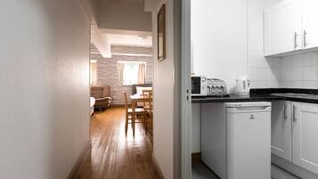 A compact kitchen with white cabinets, a built-in microwave, and a compact refrigerator.