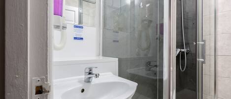 A modern bathroom with a white sink, a glass shower enclosure, and a visible hand dryer.