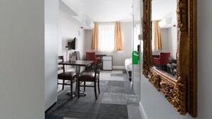 A hotel room with a dining area, a small kitchenette, and a large ornate mirror. - Central Hoxton Shoreditch (London)