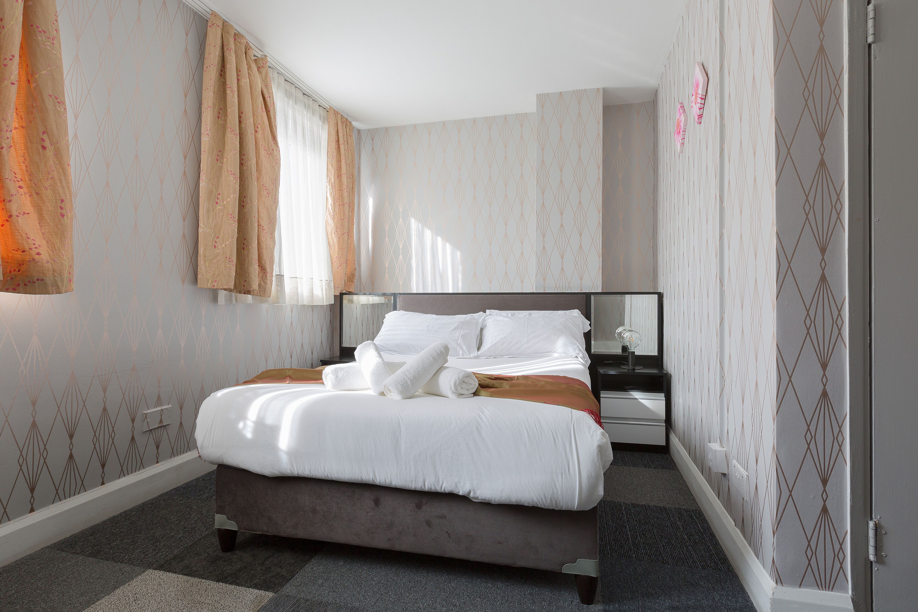 Moderni hotellihuone, jossa on suuri sänky, yöpöytä ja peili.