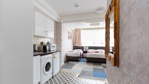 A compact hotel room with a washing machine, a bed, a bedside table, and a large mirror. - Central Hoxton Shoreditch (London)