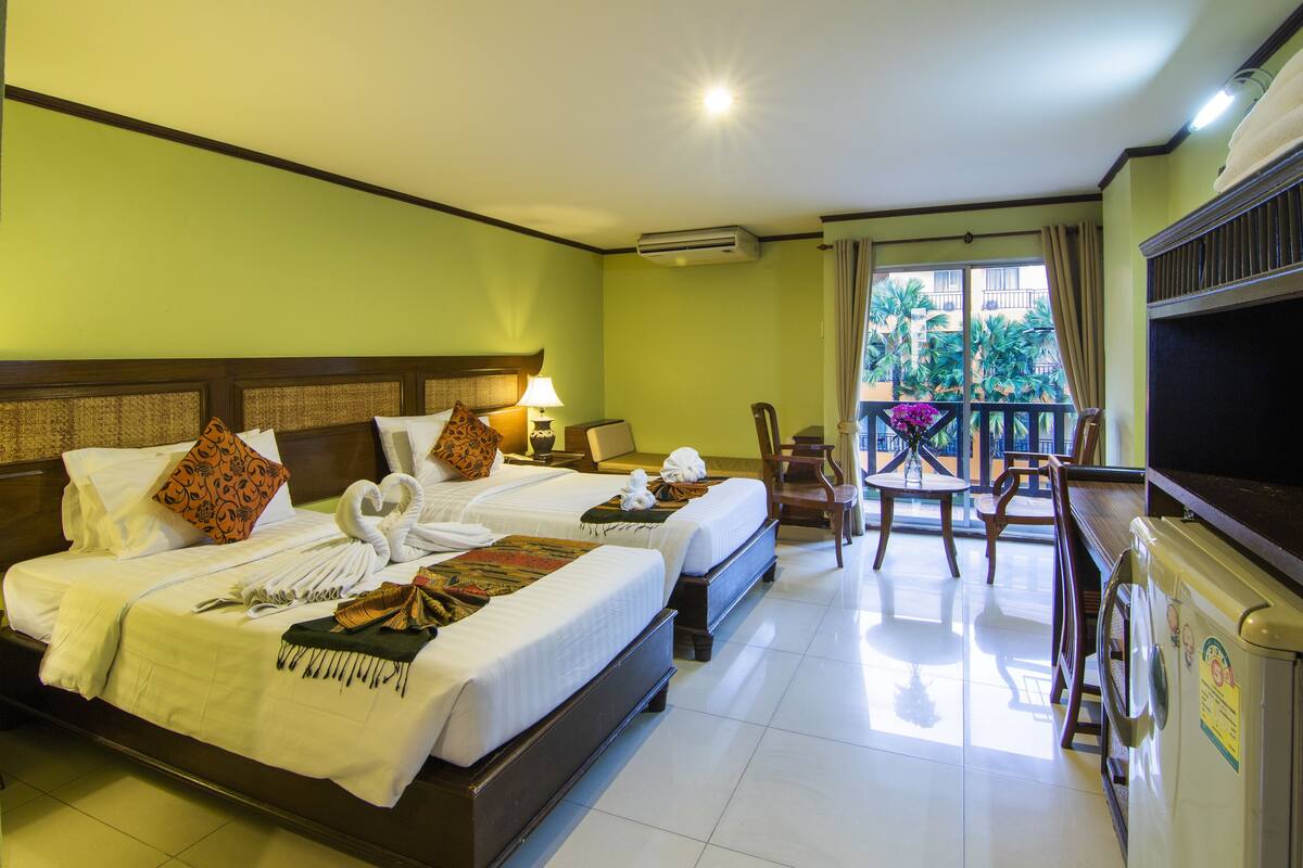 A hotel room with two beds, a balcony, a TV, and a minibar.