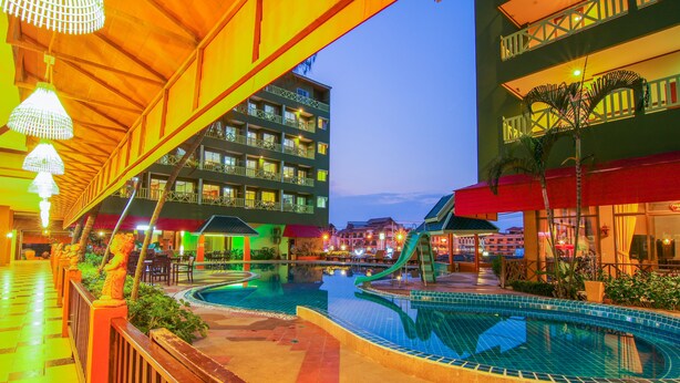 A hotel pool area with a water slide, multiple balconies, and outdoor seating. - Phuphaya Resort Pattaya (Pattaya)