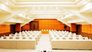 Un amplio salón de conferencias con filas de mesas dispuestas para un evento formal.