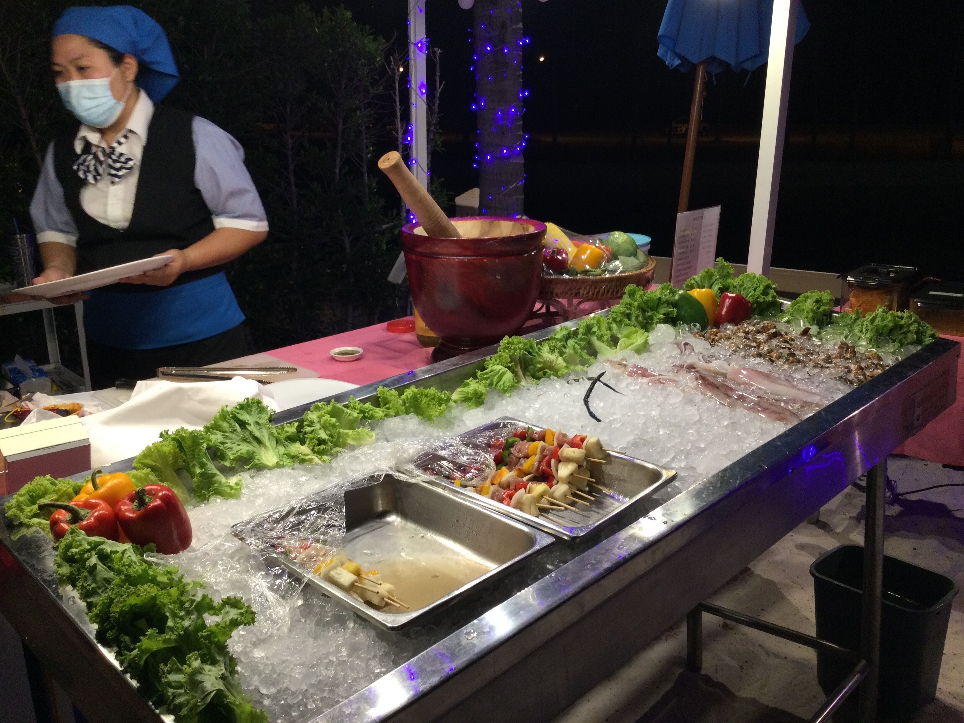 Ein Buffet mit verschiedenen Speisen auf einer Eisschicht, darunter Spieße und frisches Gemüse.