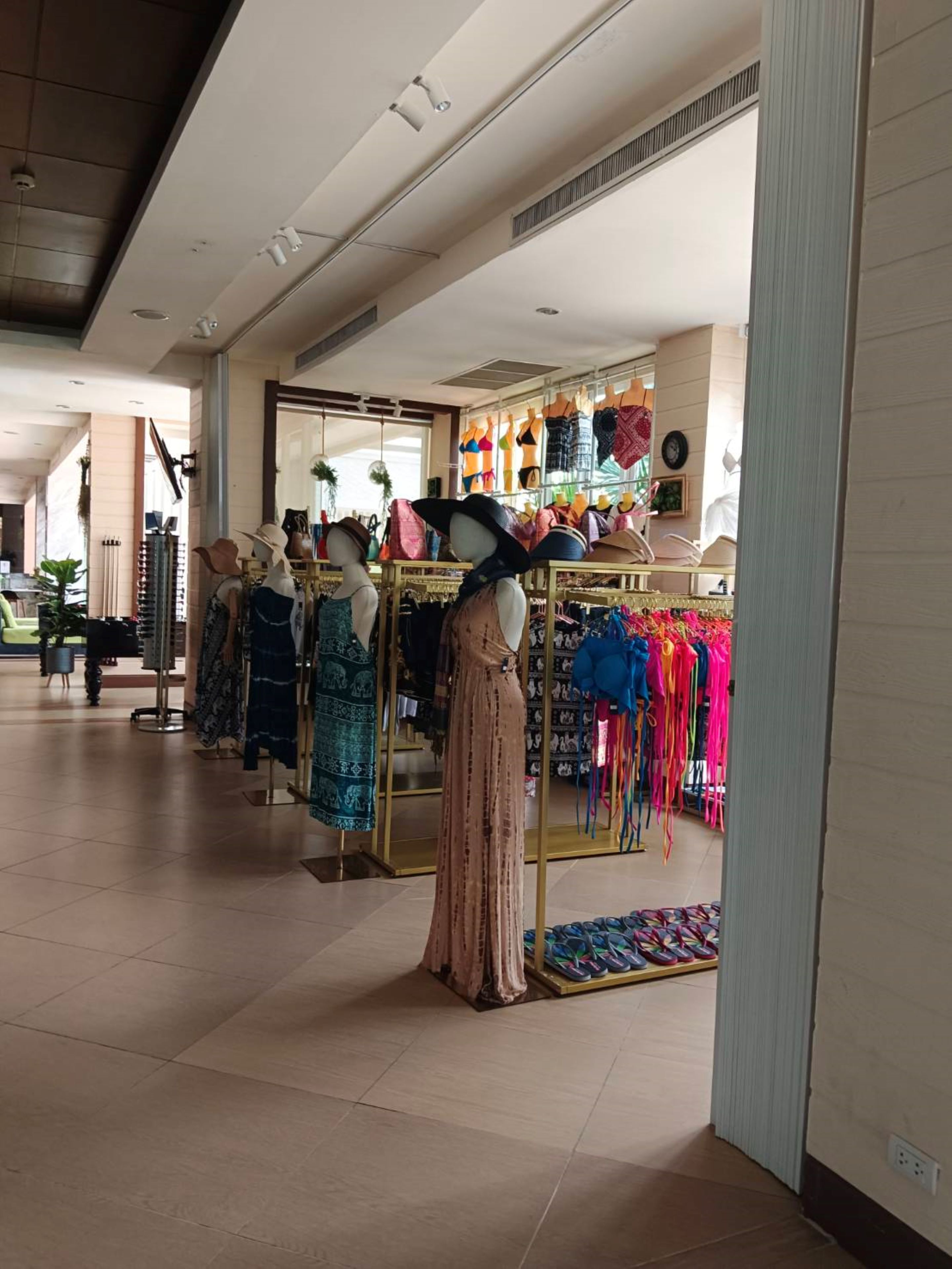 A clothing store with mannequins displaying dresses and hats.