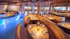 A restaurant with wooden boat-shaped tables and benches, large windows, and a nautical theme. - Hotel Victory Therme Erding (Erding)