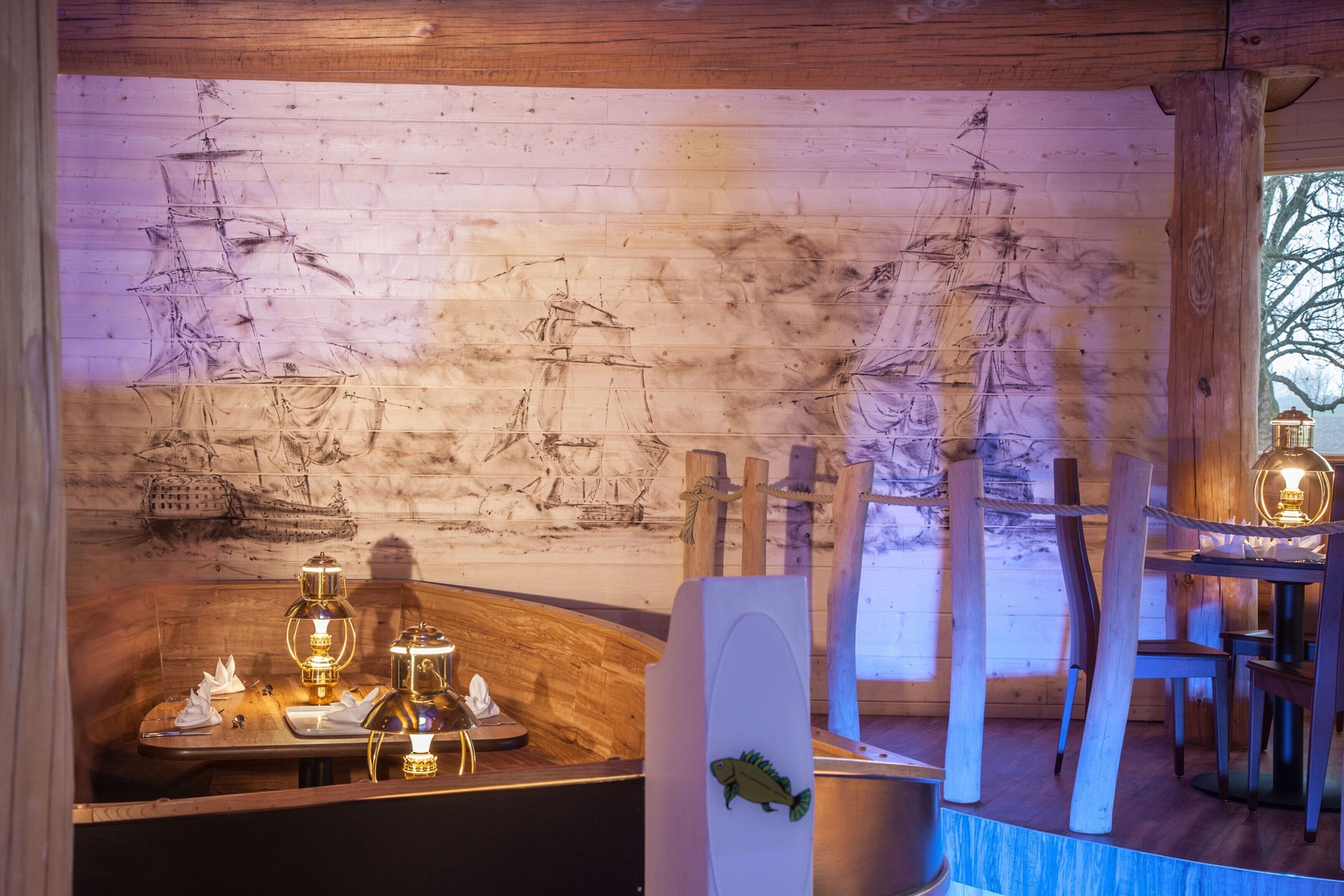 Interior de madeira com um mural de parede de tijolos, uma mesa de madeira com uma vela e uma cadeira de madeira.