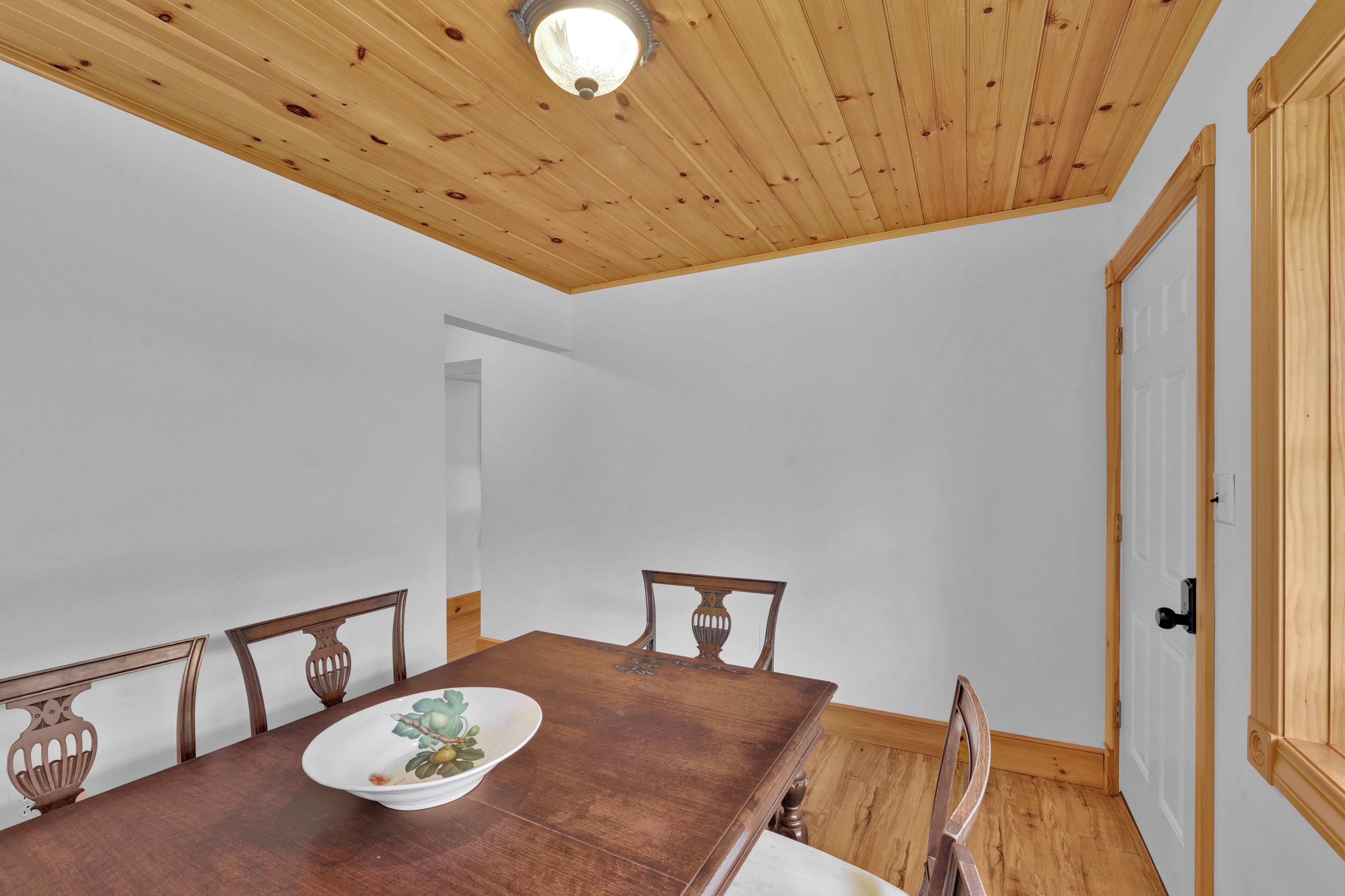 Ein Esszimmer mit einem Holztisch, Stühlen und einer weißen Wand.