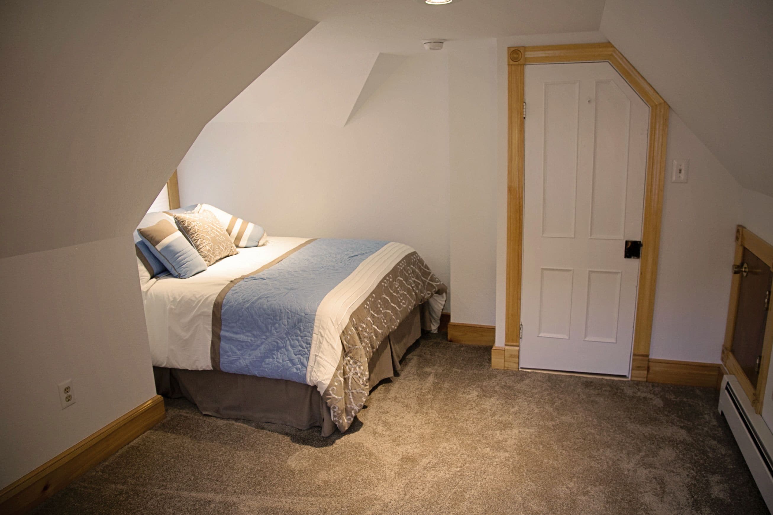 Un dormitorio con cama, puerta y radiador.