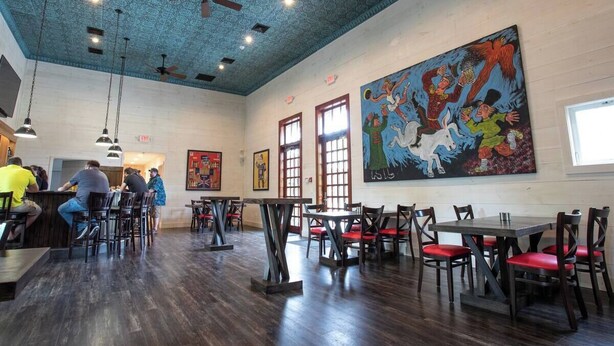 A restaurant interior with wooden floors, ceiling fans, and red cushioned chairs. - Blue Hill Lodge (Claryville)