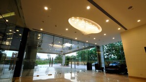 Um hall espaçoso com piso espelhado, janelas amplas e um lustre moderno.