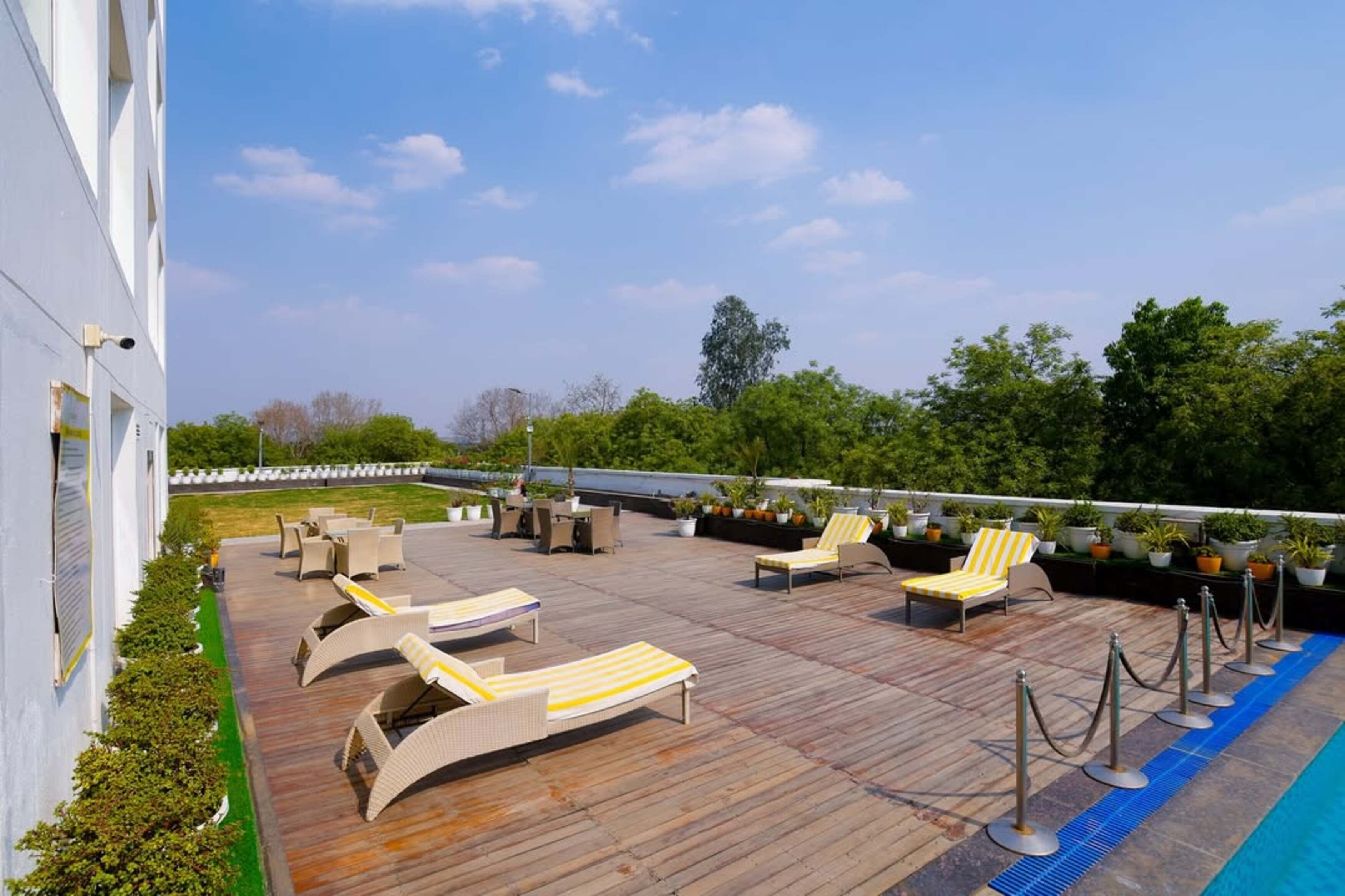 Une terrasse sur le toit avec des chaises longues et une piscine.