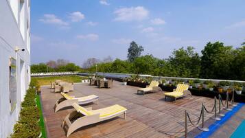 Une terrasse sur le toit avec des chaises longues et une piscine.