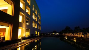 Um hotel moderno com piscina, refletindo o edifício e as árvores.