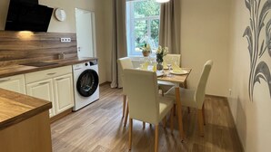 A modern kitchen with wooden countertops, a built-in washing machine, and a dining area with a table and chairs. - Penzion Jasmín (Liberec)