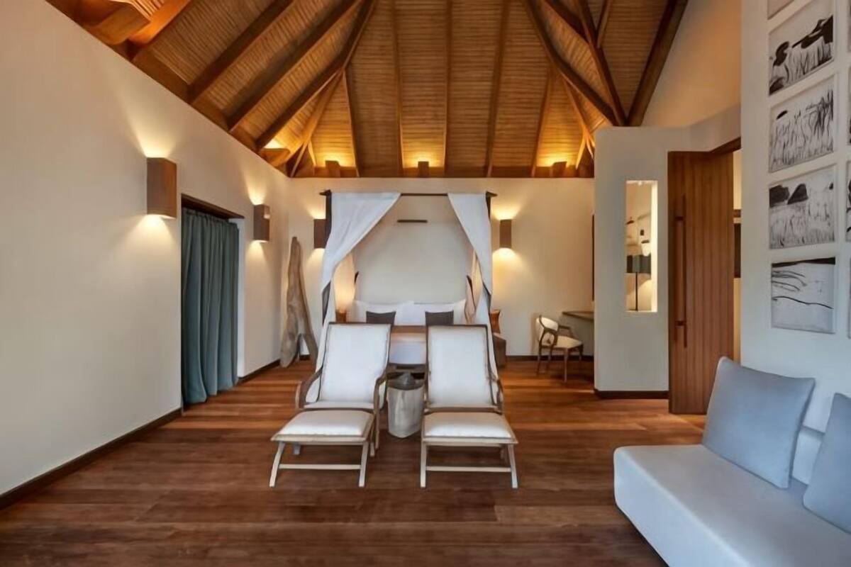 Una habitación amplia con techo alto, una cama con dosel, un sofá y una pequeña mesa.