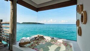 A balcony with a view of the sea, a wooden deck, and a bathtub with towels and flowers. - SONG SAA PRIVATE ISLAND (Koh Ouen)