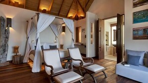 A room with a four-poster bed, two upholstered chairs, a sofa, wooden flooring, and a high ceiling with exposed beams. - SONG SAA PRIVATE ISLAND (Koh Ouen)