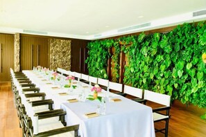A conference room with long tables, chairs, and a green wall with plants. - SONG SAA PRIVATE ISLAND (Koh Ouen)