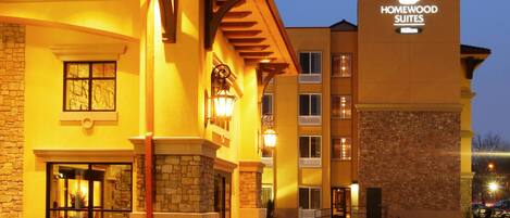 A hotel with a stone facade, a sign for Homewood Suites, and a brick-paved entrance.