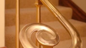 A spiral staircase with a golden handrail and beige carpeted steps.