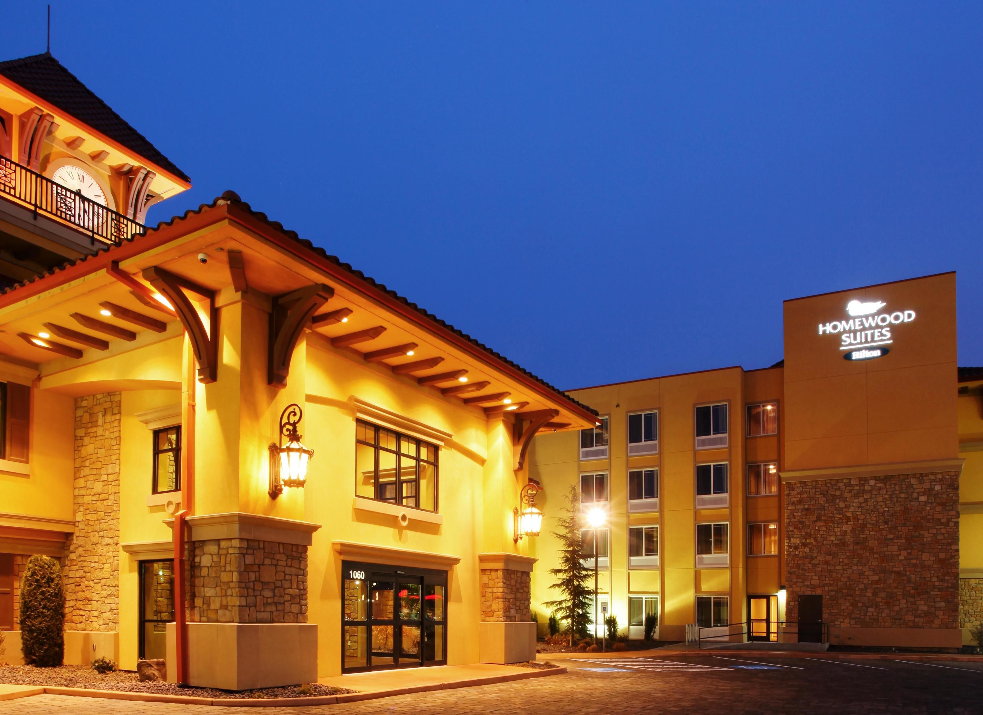 A hotel with a stone facade, a balcony with a clock, and a sign for Homewood Suites.