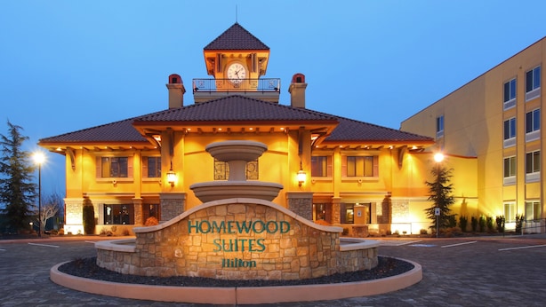 Un hotel con fachada de piedra, una torre del reloj y un cartel que dice "Homewood Suites Hilton".