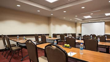 A conference room with multiple tables, chairs, and a projector screen.