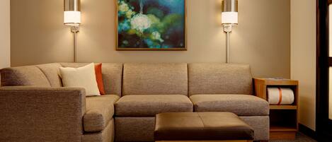 A modern living room with a sectional sofa, a wooden bench, and two wall-mounted lamps.